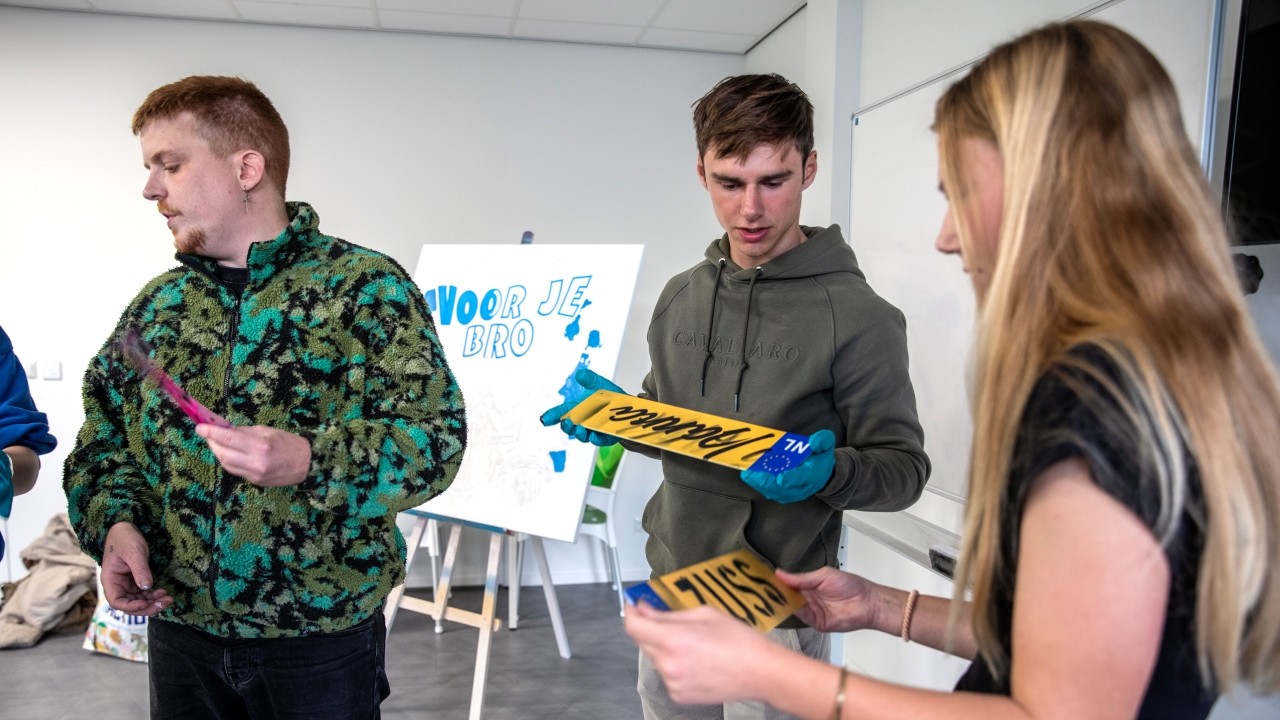 Kunstenaar Jochem van Aller met jongeren aan de slag om kentekenplaten te voorzien van graffiti