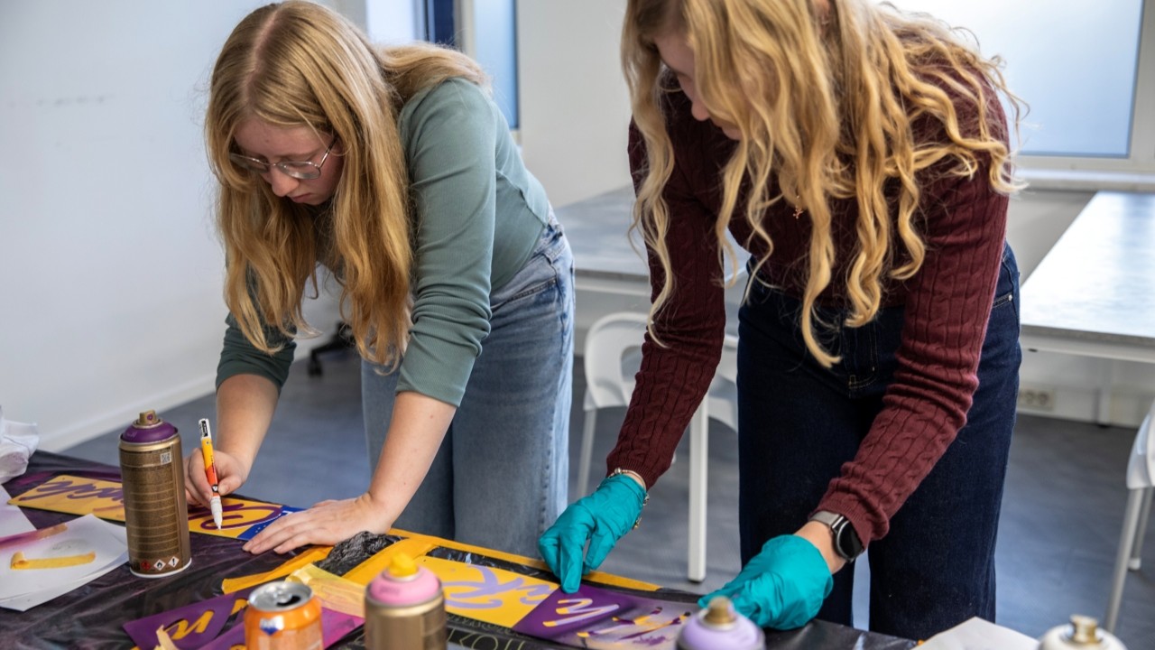 Twee deelneemsters aan de slag in de graffiti workshop