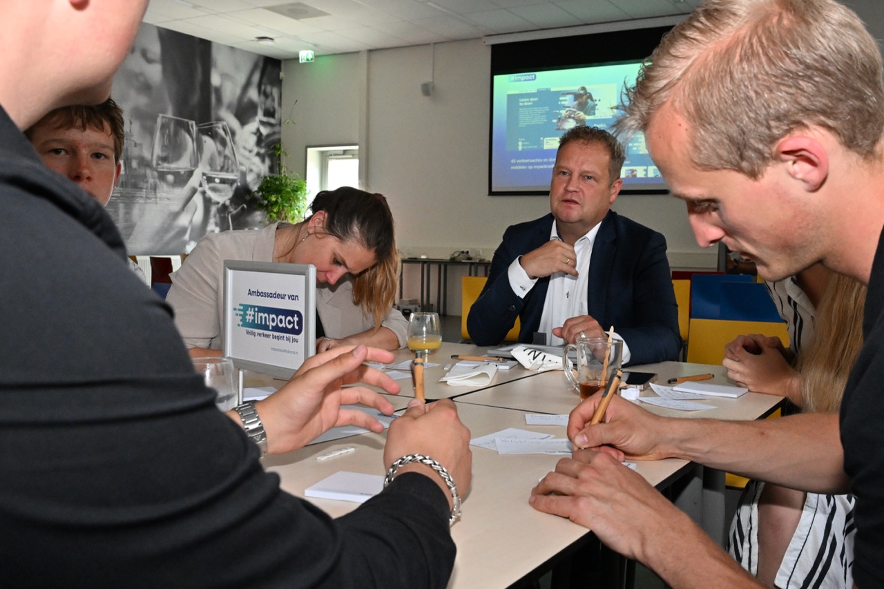 Deelnemers, die aan een tafel hun acties opschrijven
